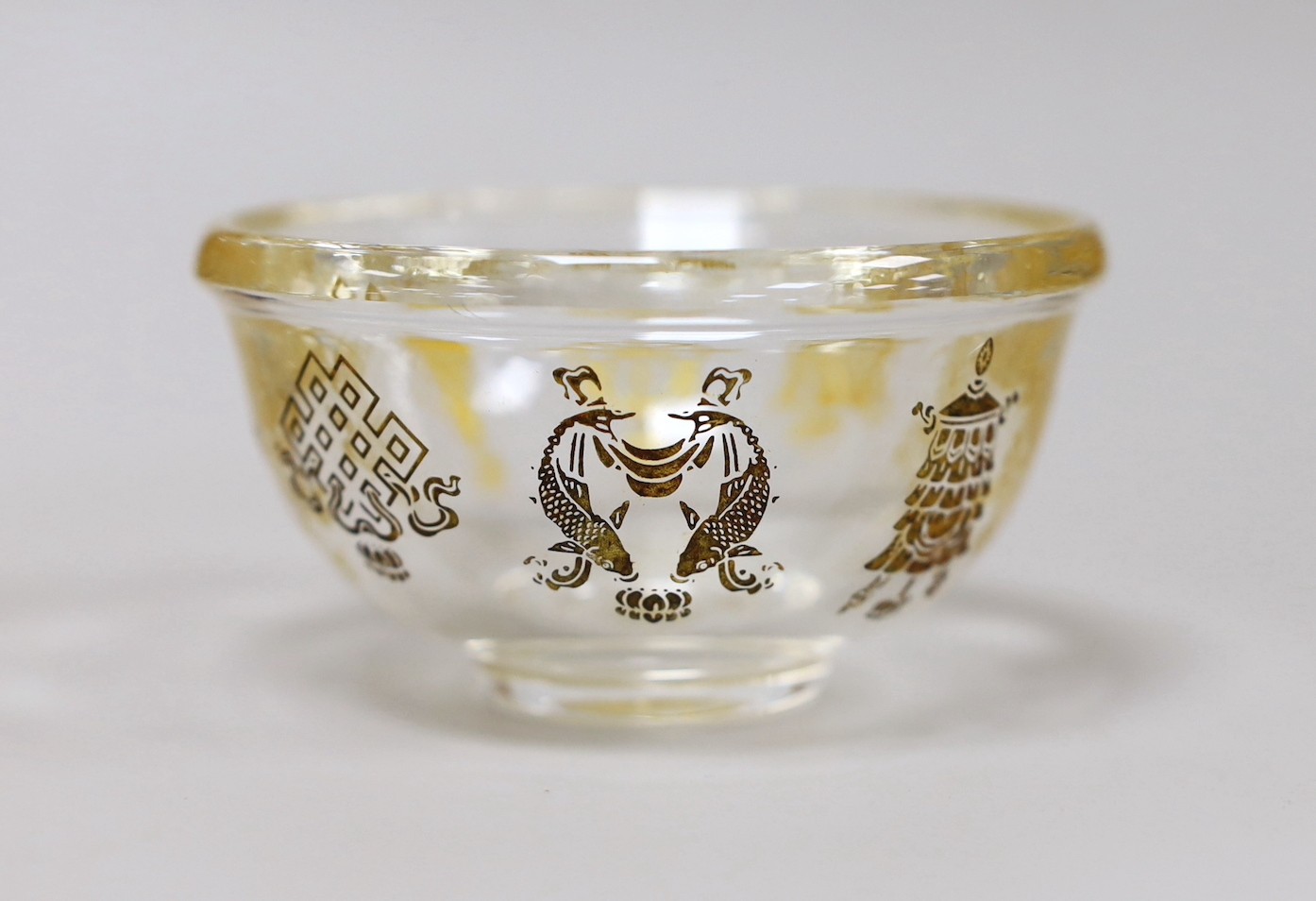 A Tibetan glass gilt decorated 'eight Buddhist emblems' bowl, 9cms diameter